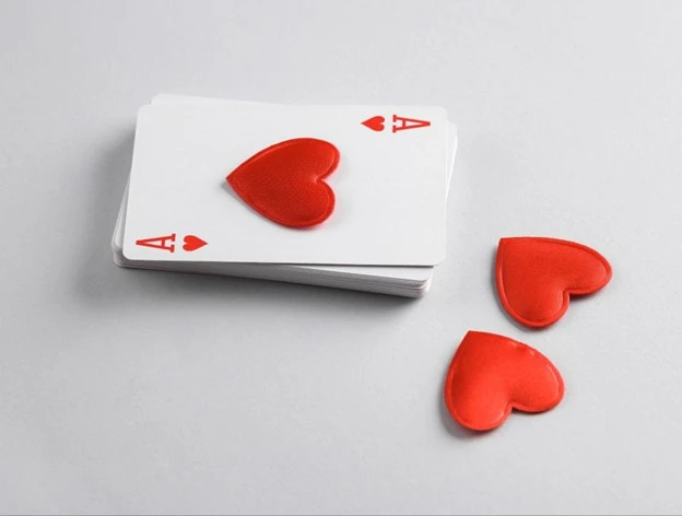 A deck of cards with the ace of hearts face up on top.