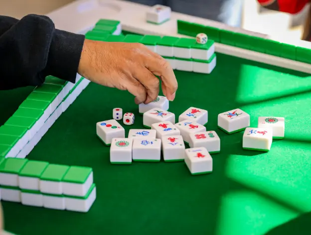 A hand reaching for mahjong tiles
