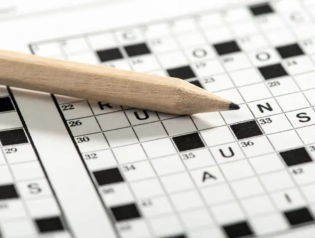 A closeup of a pencil and paper crossword in progress